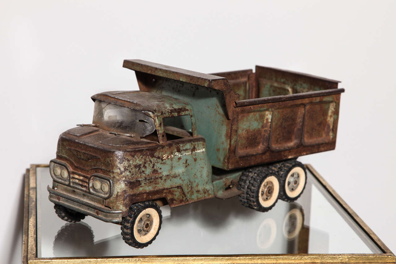 Pressed steel vintage toy truck with movable wheels and loading door. Original glass and windshield wipers. The loading part has a working mechanism to tilt it back.