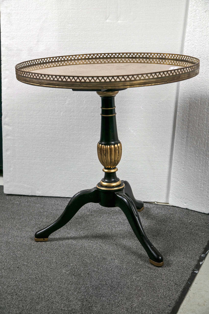 Pair of French Louis XVI style side tables by Jansen, circa 1940s, the circular gilt-glass top with brass banding, supported on a single ebonized and parcel-gilt pedestal, heading to a tripod base.