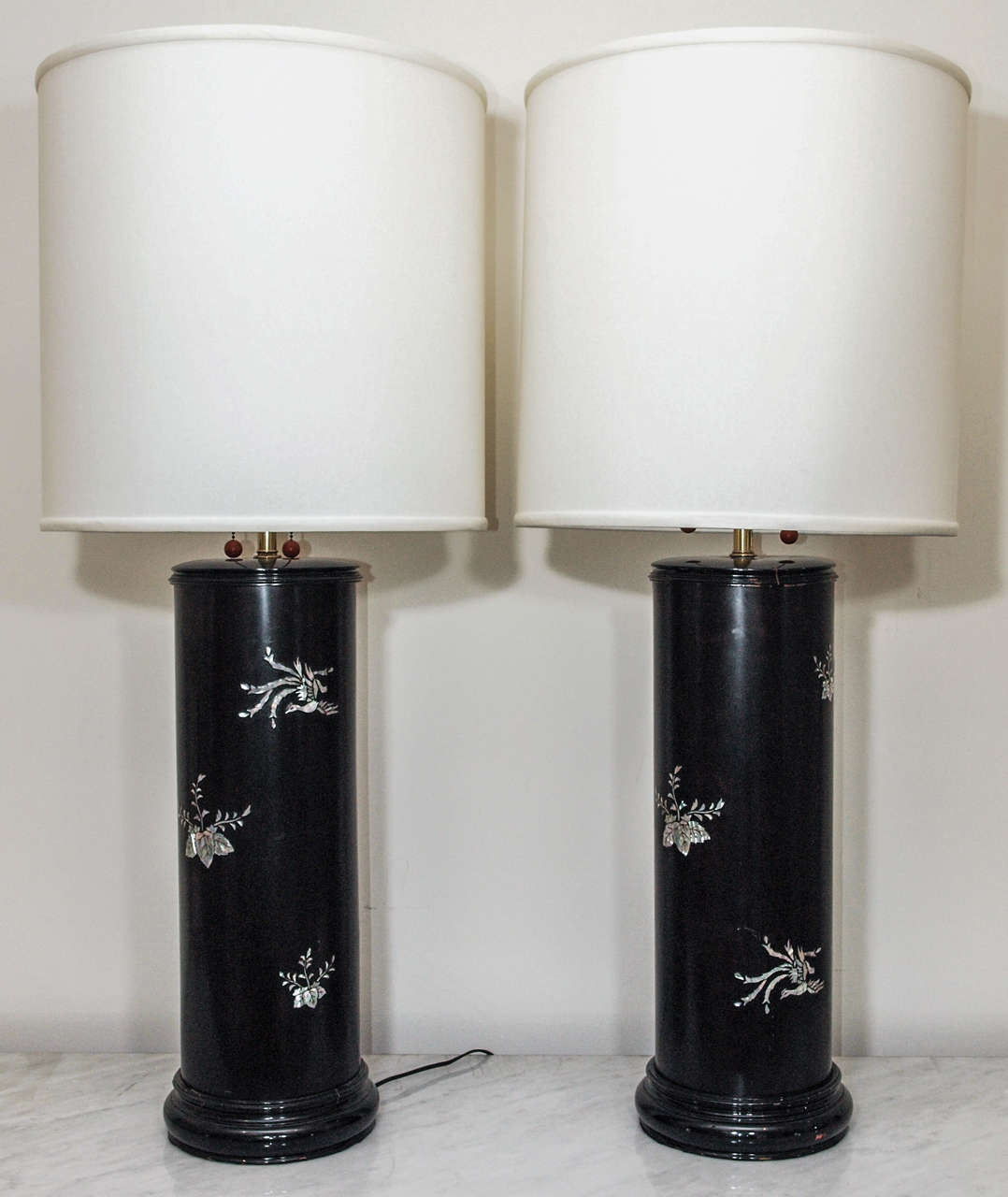 Two quite large table lamps in ebonized wood with intricate inlay in mother-of-pearl; each having two lights with individual pull chains; drum shades in ivory silk; base measures 8.5" diameter