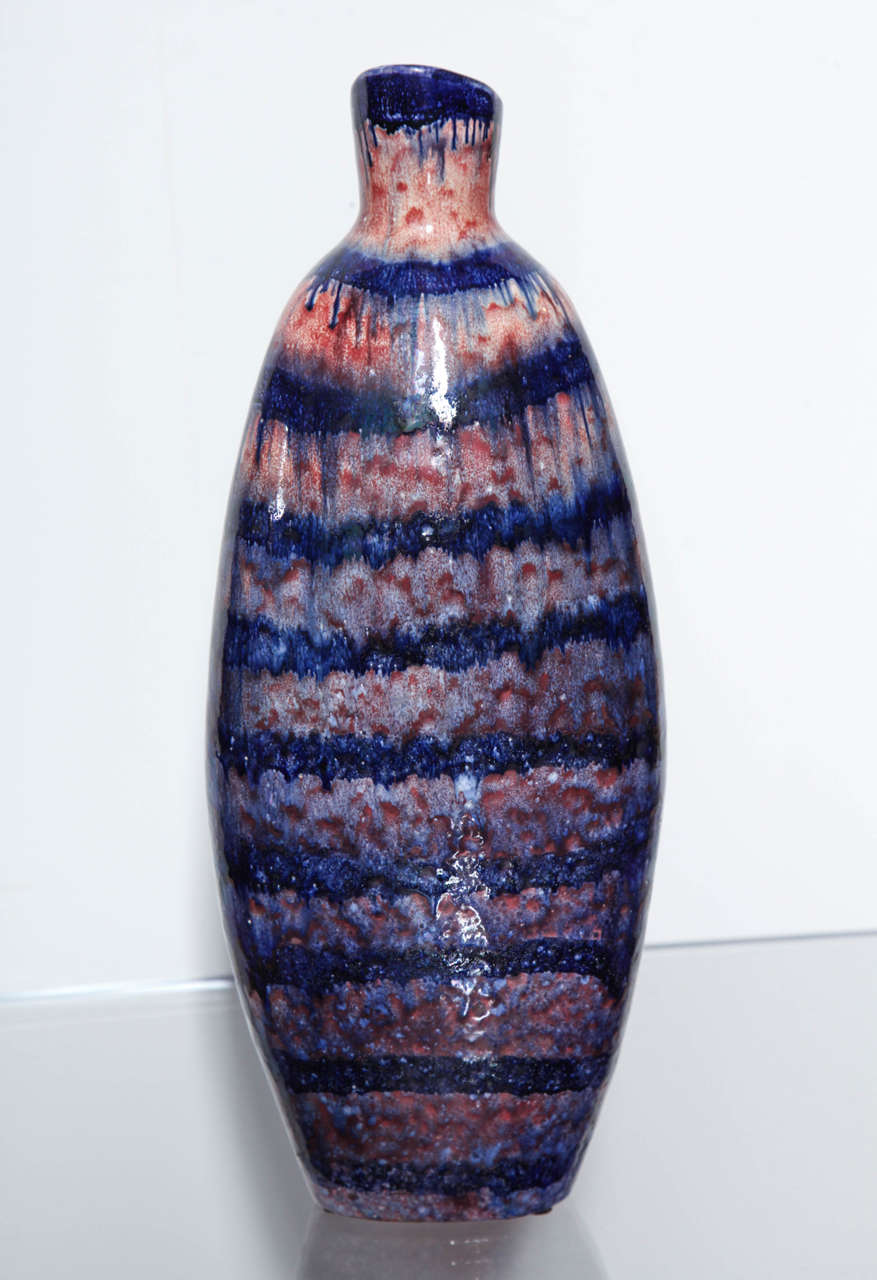 Handgefertigte Keramikflasche von Torviscosa. Unregelmäßige Flaschenform mit schräg abgeschnittener Mündung im oberen Bereich. Hochbrandglasuren in gesprenkelten Rot- und Blautönen erzeugen einen schönen Effekt. Wirklich schönes Beispiel für