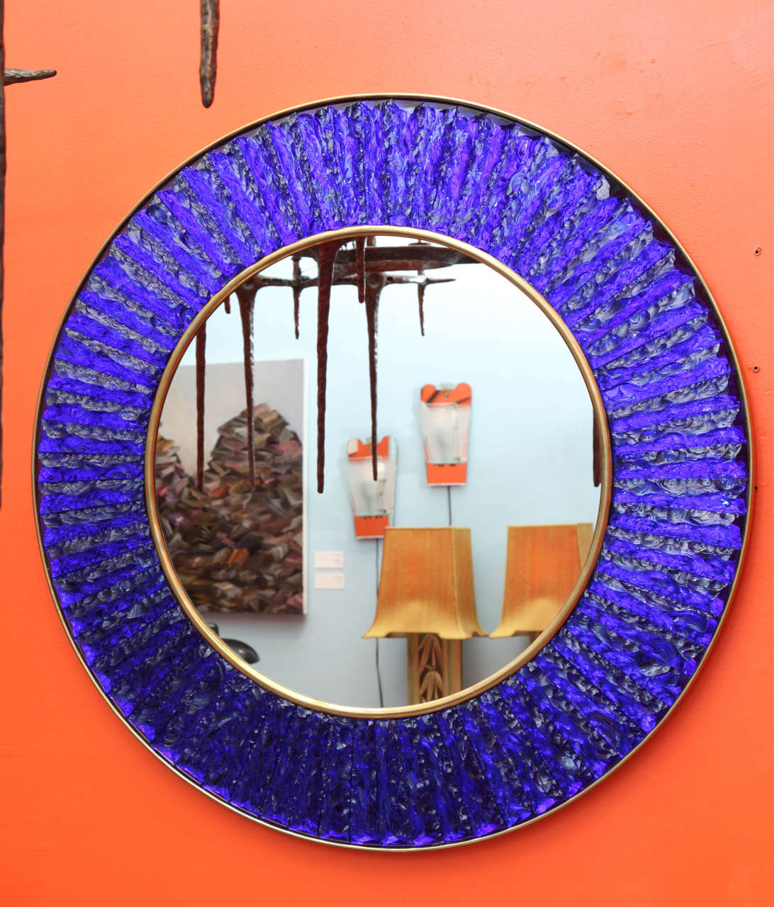 Contemporary wall mirror of hand-cut and chipped chunks of sapphire blue glass. Arranged in a circle around a central mirror with brass mounts. Beautiful studio made piece created exclusively for Donzella. Signed on side edge.