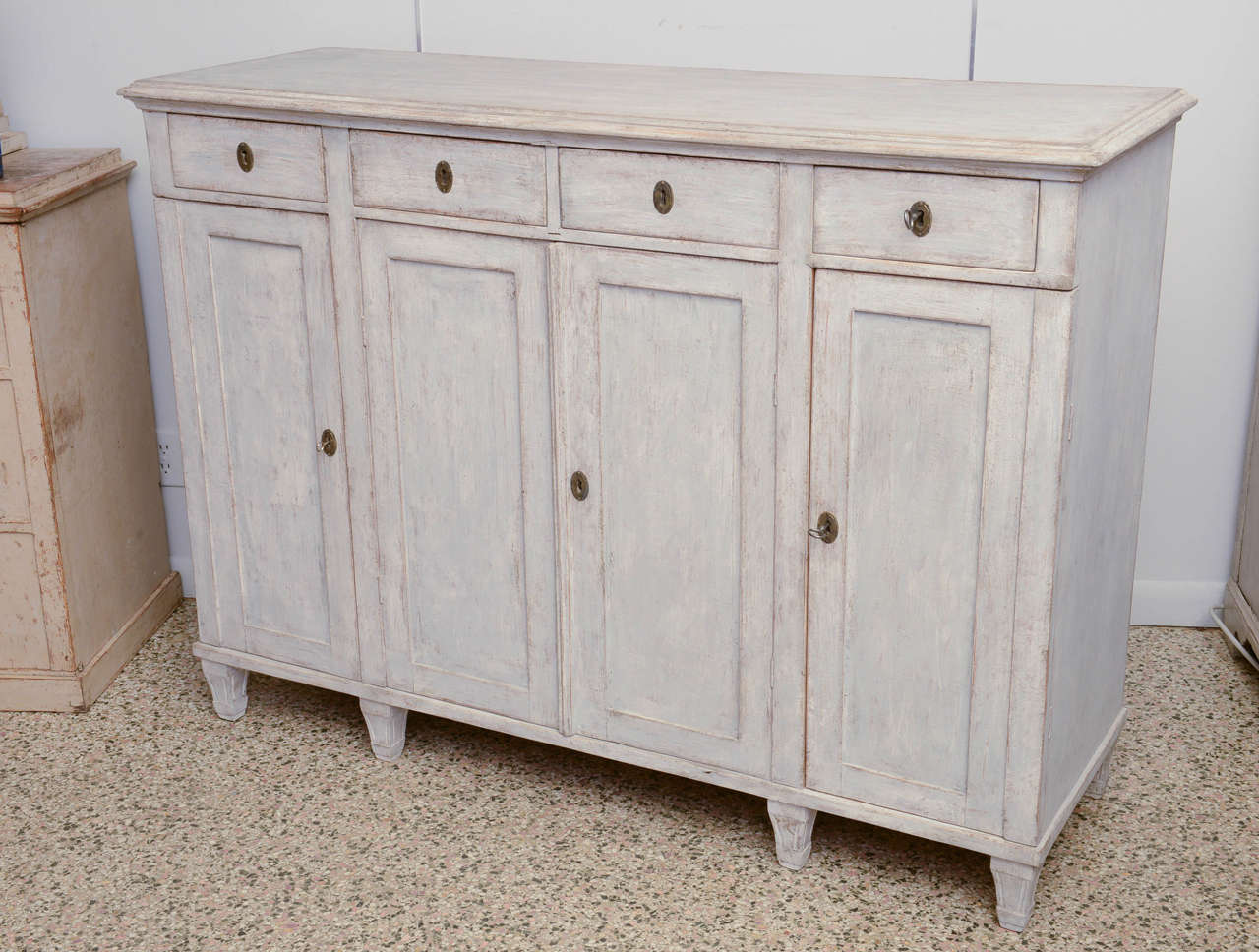 Antique elegant Swedish painted sideboard in simple design, late 19th century.

Cabinet has rounded top moulded edge, four small drawers above and below are single side doors with double doors in centre; on fluted legs. The shelves inside are
