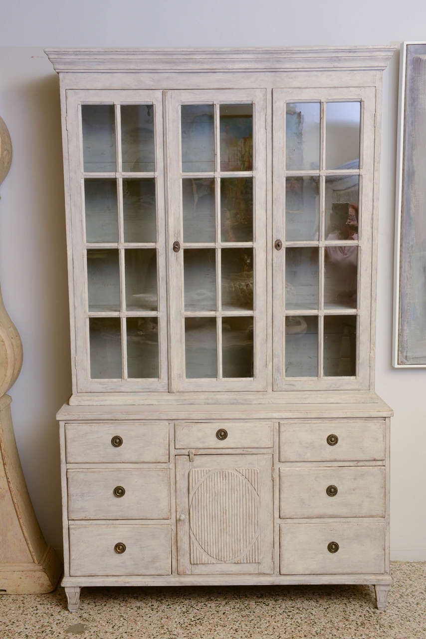 Gustavian glass cabinet in two pieces; upper left part has original double glass doors with three shelves and upper right part has original single glass door with three shelves. The lower part has six large drawers and a small center drawer that