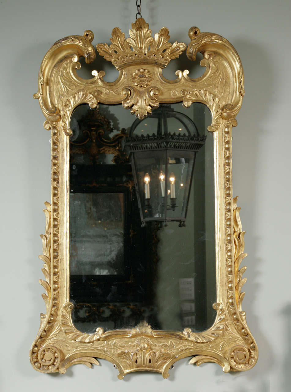 With scroll arch pediment surmounted by a coronet and C scrolls above a rectangular plate surrounded by a stiff leaf and acanthus decorated frame. 
Circa 1740, possibly Irish.