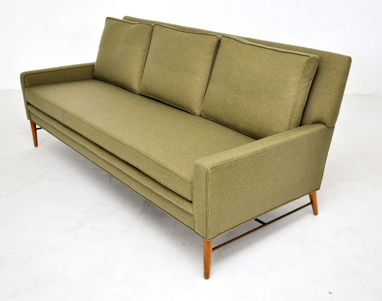 Paul McCobb sofa.  Newly upholstered in moss green linen.  Original finish birch legs with brass stretchers.