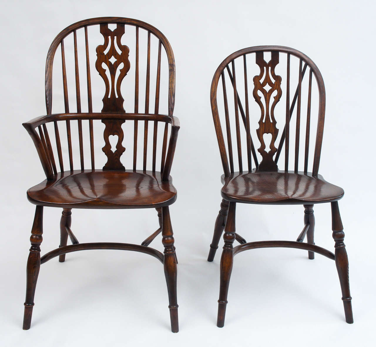Stunning grain on this set of early 20thC English oak Windsor dining chairs. The design of the set was based on earlier sack back Windsors; design characteristics include saddled seats and curved stretchers. This exceptional set includes eight side