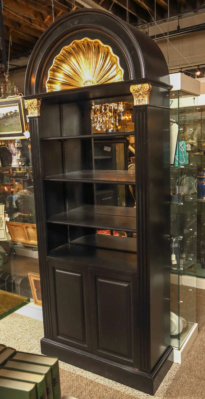 Pair of shell form, ebonized, mirrored back cabinets by Maison Jansen. The very elegant bracket base bottoms having double doors hiding interior shelving. The bottom leading to Corinthian Column form sides with gilt capitols and a finely gilt upper