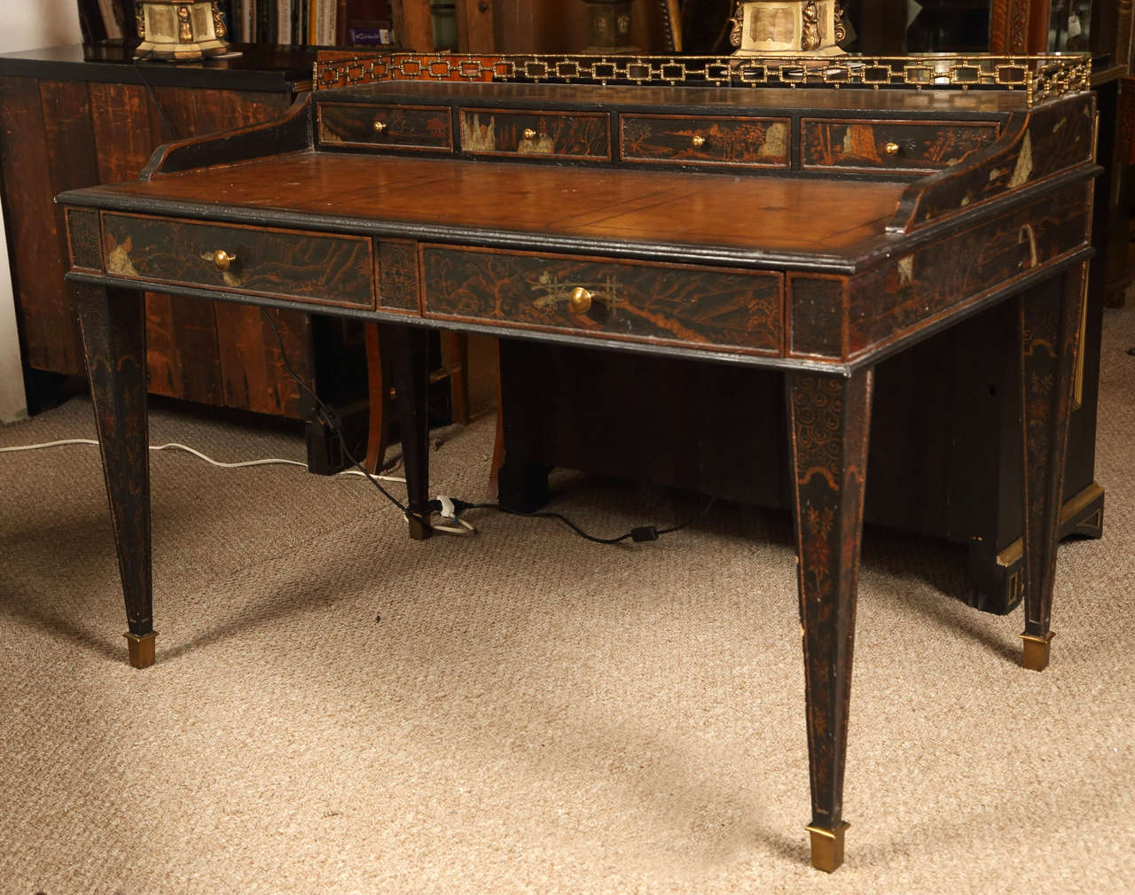 A Maitland Smith Chinoiserie Carlton House Desk. The bronze sabots leading to tapering legs with all over Chinoiserie decoration supporting a four over two drawer step up desk with a tooled leather writing service. The top tier with a bronze bamboo