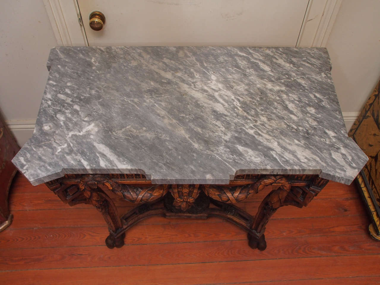 Unusual French Louis XVI Console Table with Swag motif across the front and sides all culminating in a cartouche in the center with a shaped gray marble top. 
The form is unusual as it has two from support legs and one rear one with a trifed base.