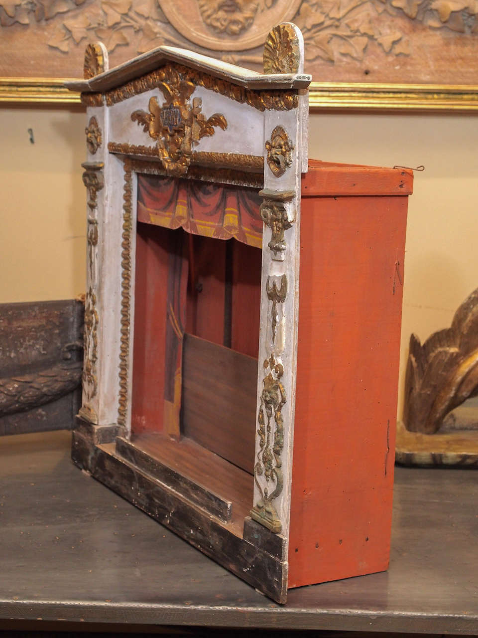 A painted wood frame with classical gilt appliques on the sides and a gilt crest saying 