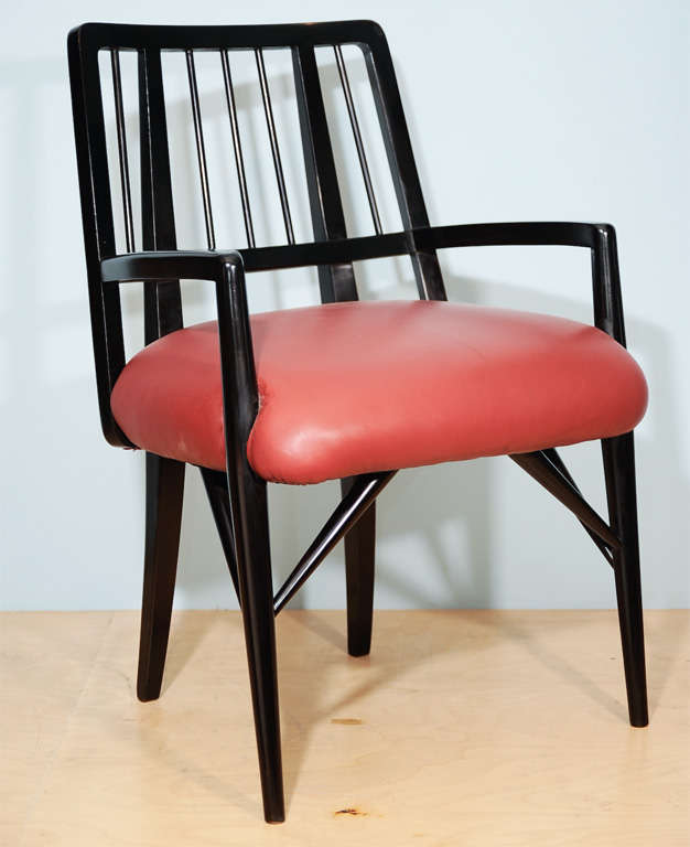 Four custom designed dining chairs by Paul László. Finished in black lacquered wood with spindle backs, open arms, and architectural supports. Red upholstered seats.

Similar chairs were used in the interior of the Brentwood Country Club, as