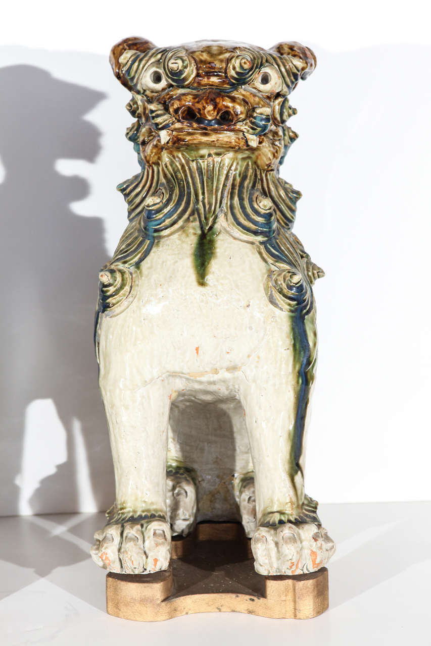 Pair of left and right, painted and glazed, ceramic Foo Dogs on gilded stands.