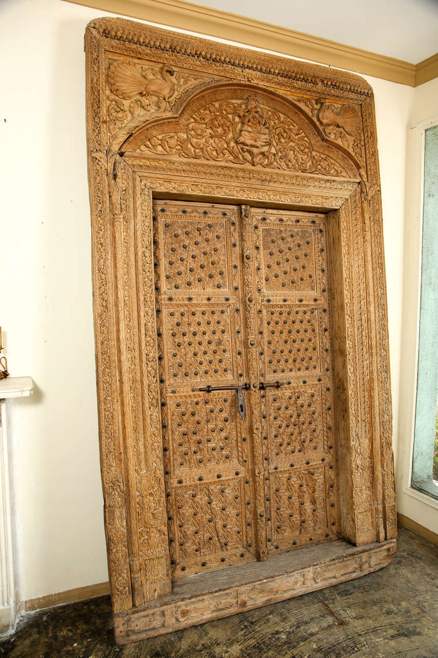 Made of an Indian hardwood called Shagun which doesn't wrought in water. About 200 years old. It is all hand carved and is embellished with fancy brass studs. The hinges and slide bolt are wrought iron. It has a complete door surround. Very good