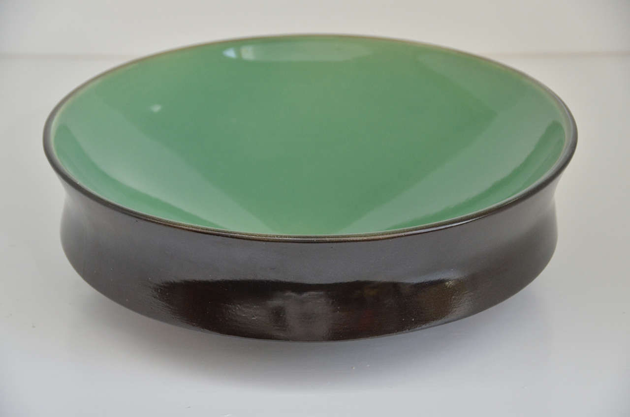 Hand thrown ceramic bowl with two color glazing.   Round shape with indented curved sides set on bottom platform.