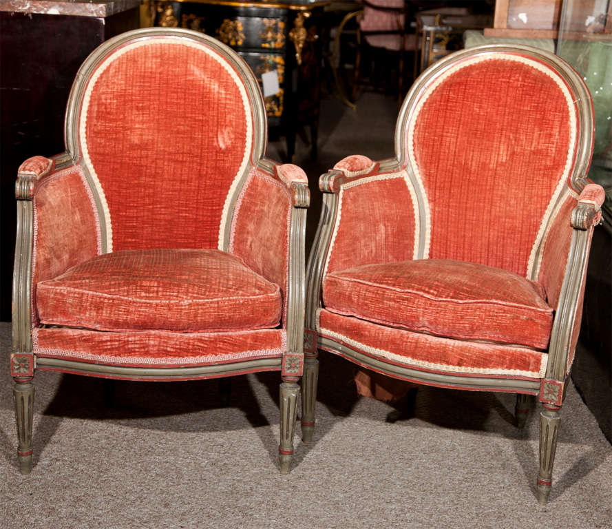 Pair of French Louis XIV style bergere chairs, circa 1920s, distressed gray painted frame, oval back, original upholstery, cushioned seat, raised on circular tapering legs ending in toupie feet. Seat height is 15.50