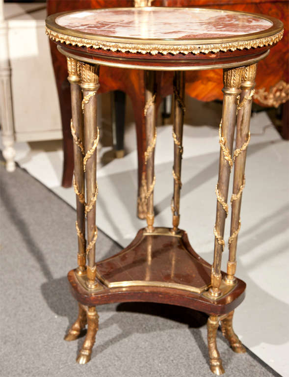 Finest quality bronze-mounted Gueridon table. French marble top sitting on a finely cast bronze gallery border held up by a set of six Louis XVI style columns all with leaf and vine carvings the lower shelf framed with a bronze sitting on six hoof