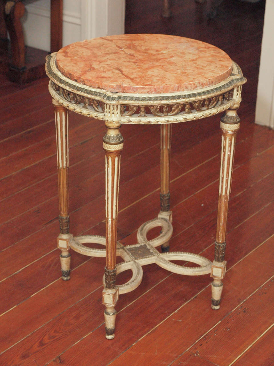 A painted Louis XVI style side table with a Rosso Verona marble top.  The apron is pierced, and the fluted legs joined with an elaborate stretcher.