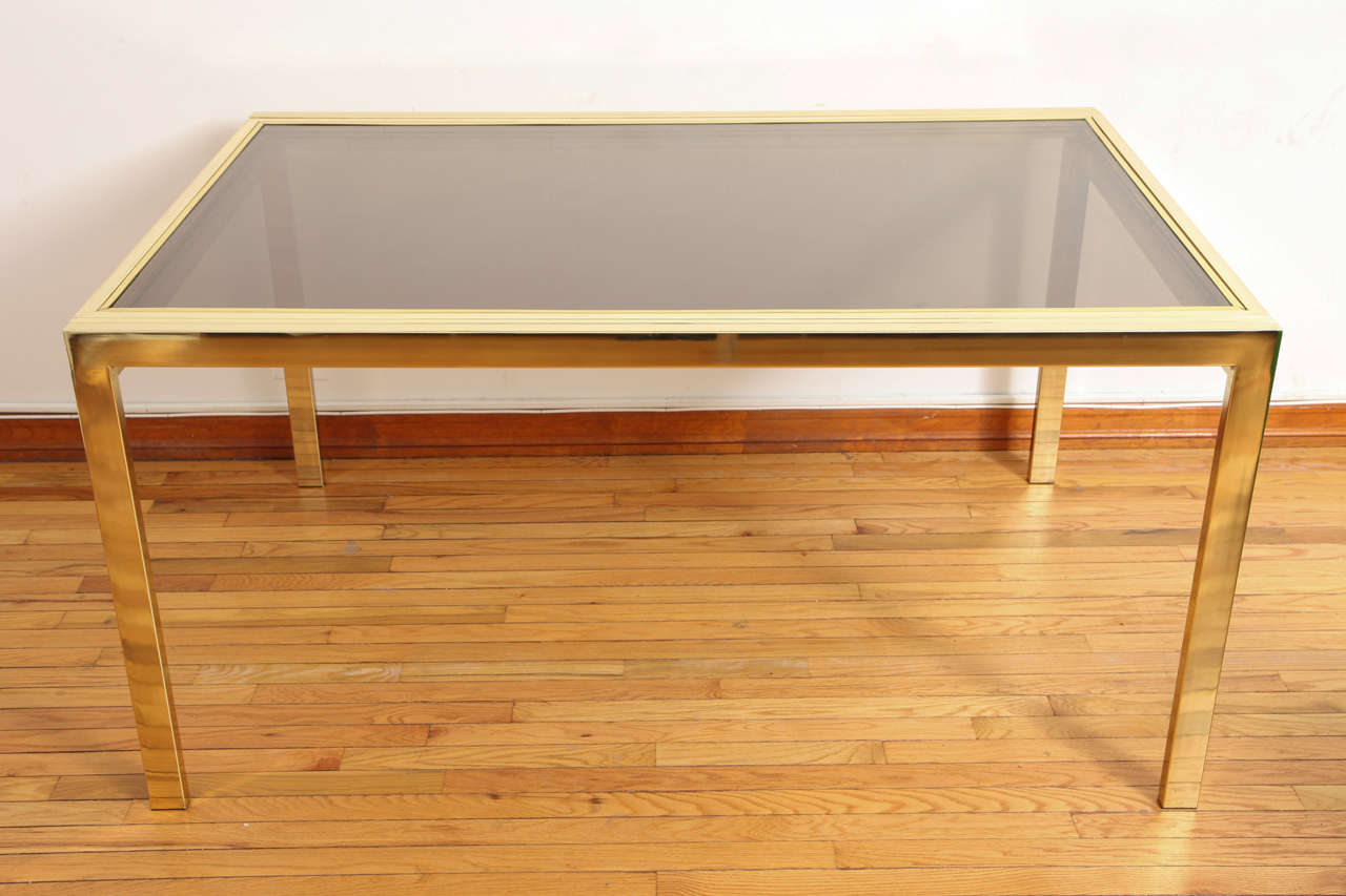 Sleek extension table in brass and smoked glass by Design Institute of America c. 1970s. Measures 10 ft. in length when fully extended.