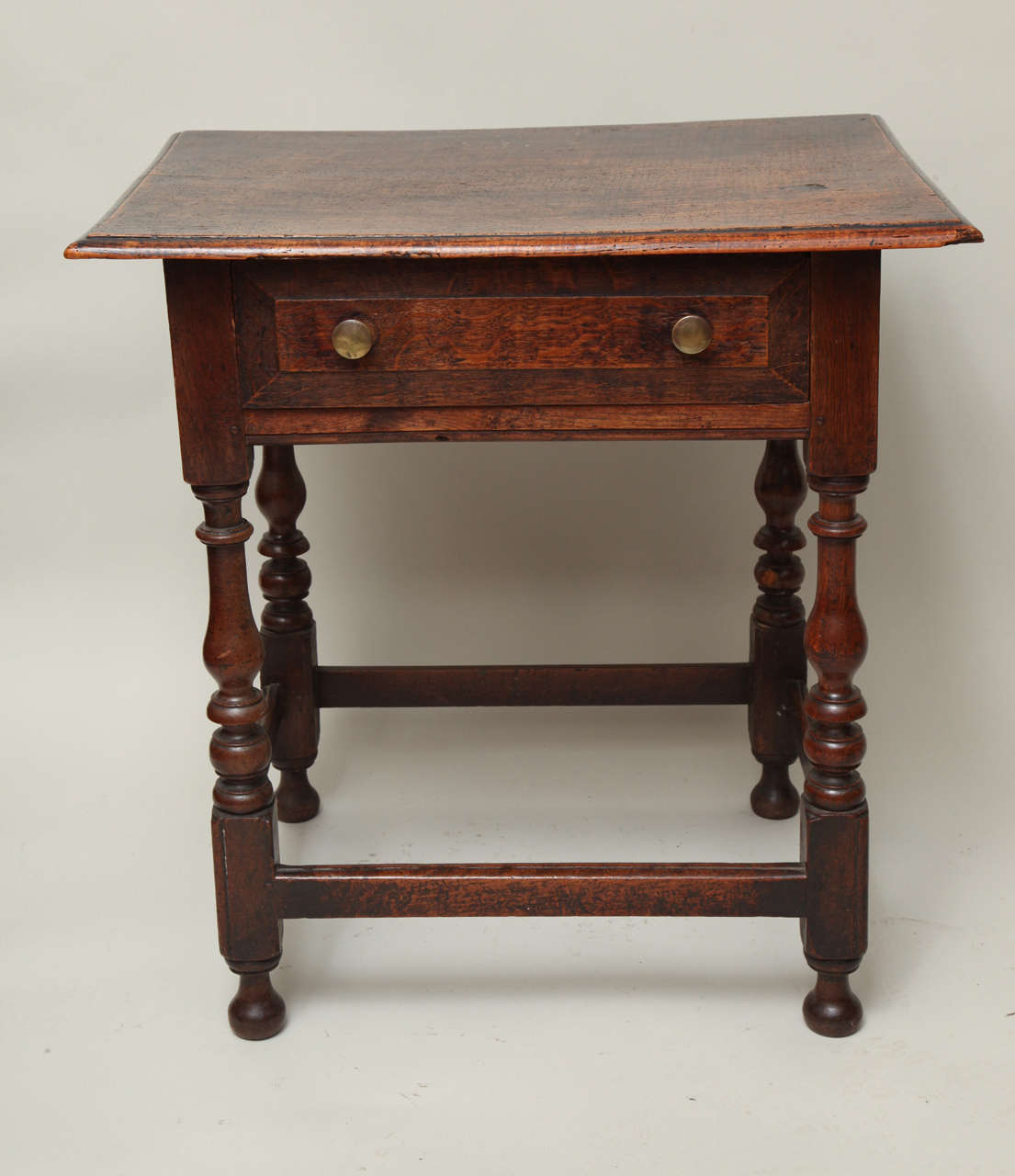Very good late 17th century English ash and oak side table, the single plank tiger ash top with thumb molded edge, over single drawer with chamfered edge, over boldly turned balustrade legs with beaded edge and original bun feet, joined by beaded
