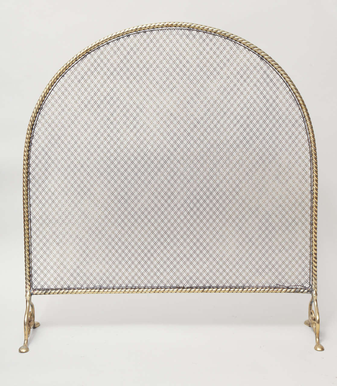 Unusual 19th Century arched fire screen having brass frame with rope twist design, standing on penny feet.