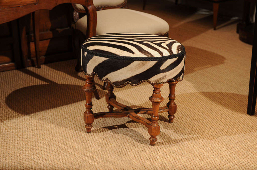 A Louis XIII style walnut stool covered in zebra skin