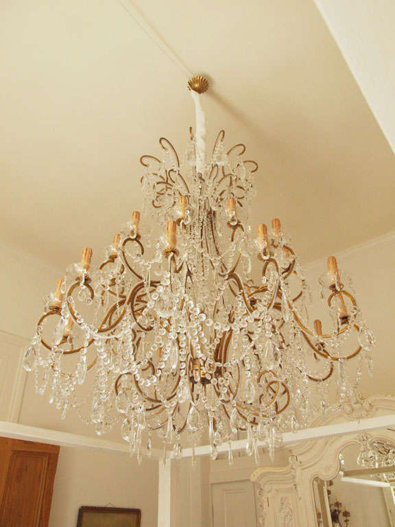 Italian crystal and gilded iron chandelier of impressive size. Handcrafted by a second generation chandelier maker in Italy with large and heavy Murano glass crystals. Crystals are individually hand knotted and tied and crystal beadings are wrapped