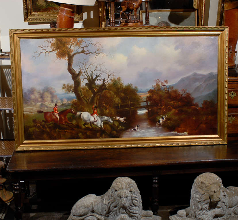 An English oil on canvas painting depicting a hunt scene from the 20th century. This horizontal format oil on canvas painting features a stylish hunting scene, depicting two riders dressed in traditional red English hunting clothes, following hounds