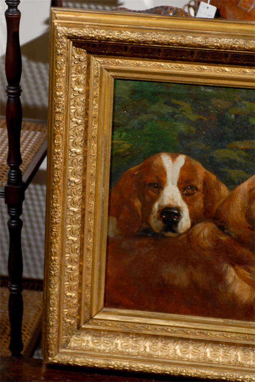 Oil painting of two dog heads in landscape in gilt frame.