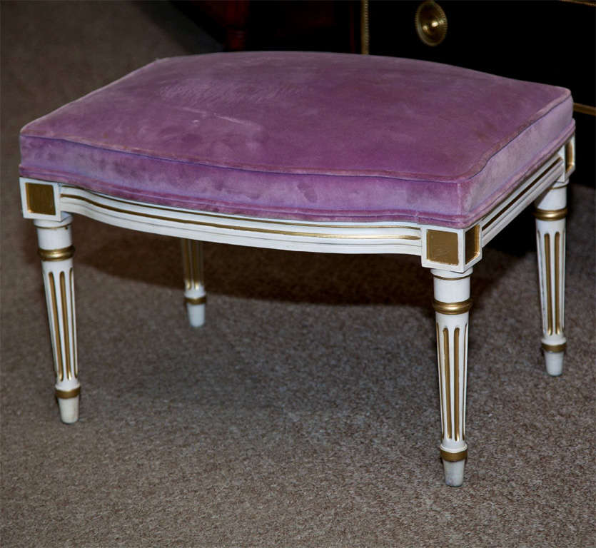 Pair of French Louis XVI style foot stools, circa 1950s, overall white painted and parcel-gilt, upholstered in purple velvet.