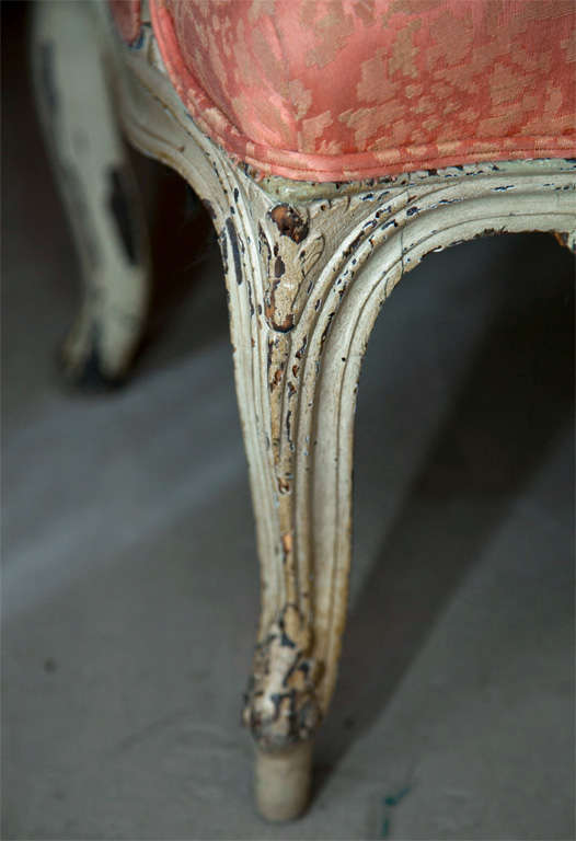 Pair of charming French Louis XV style distress-painted bergere chairs, circa 1940s, the squared back center by carved rosette crest on the top, padded down swept arms and seat, raised on cabriole legs ending in toupie feet. By Maison Jansen.