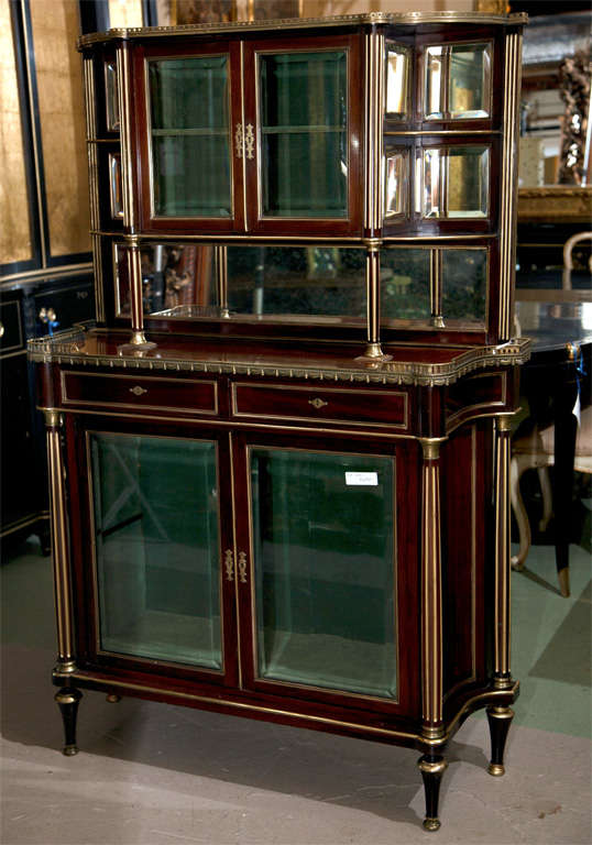 A finely made French Louis XIV style mahogany server cabinet, circa 1920s, the bow-shaped cabinet with glass doors and galleried top flanked by tiered sides, atop a narrow frieze fitted with two drawers over a cabinet with two glass doors, raised on