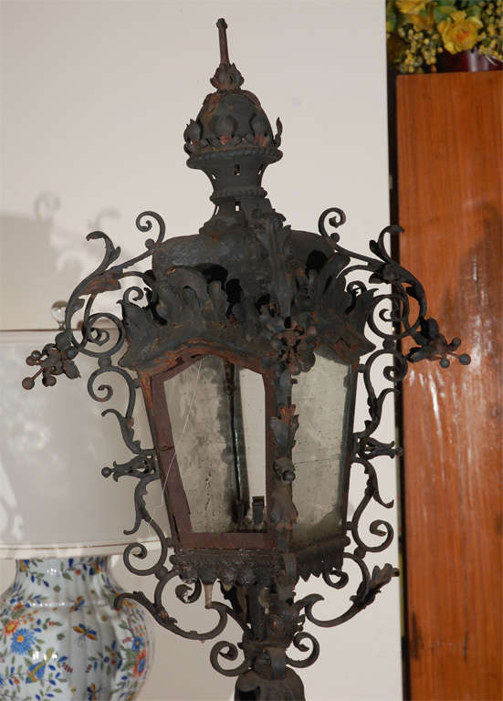 Pair of old iron torchieres on marble bases. These pieces are old and grand and have been outside a grand estate for years as candle lights. They can be changed to electric, can go in or out, and can be steam cleaned to polish the marble and smooth