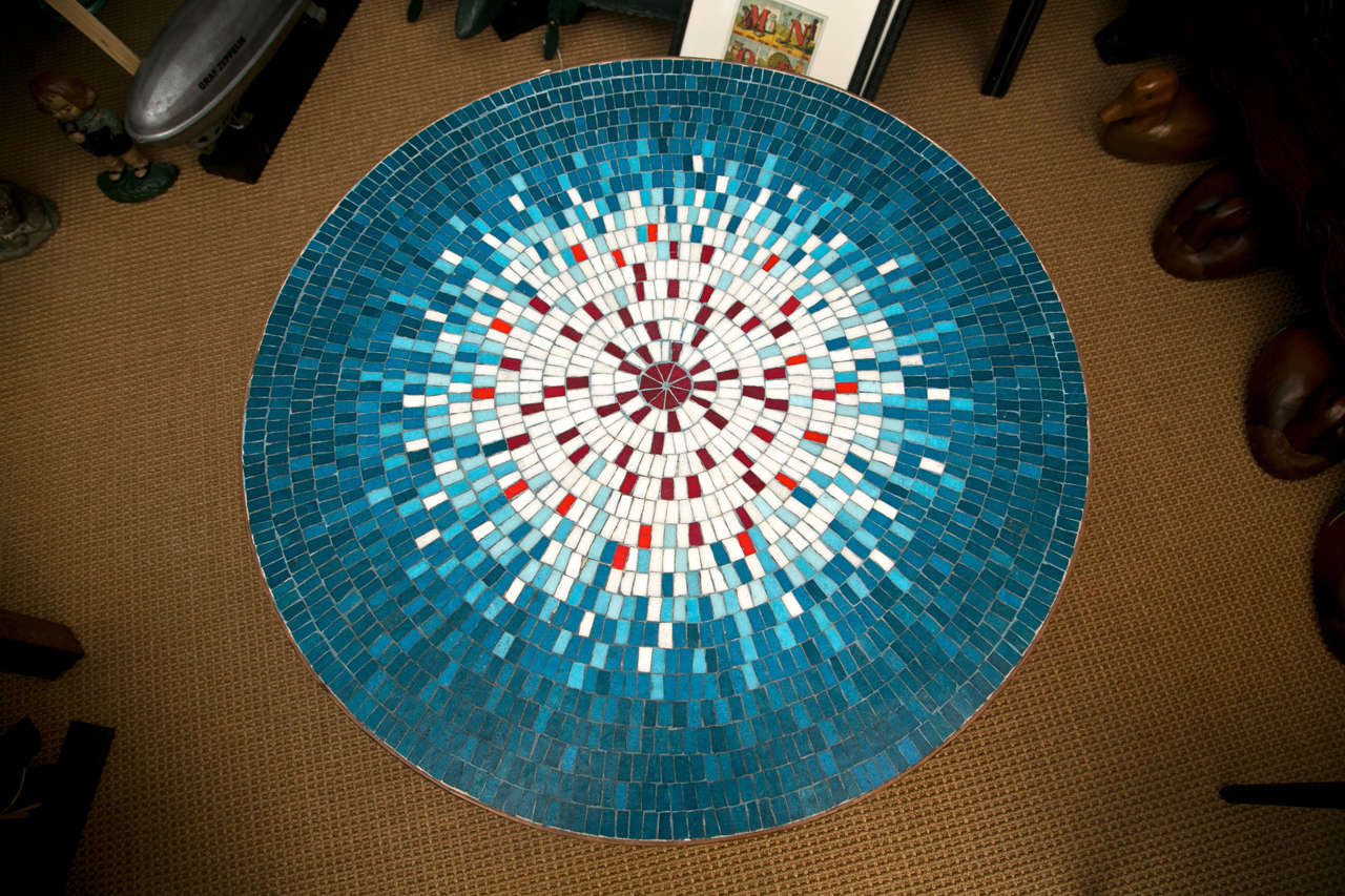A burst of blues, whites, and reds make up the top of this artist crafted mosaic tile table. The base is solid wood with an ebonized finish.