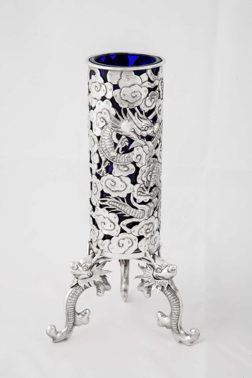 A Pair of Chinese Export Silver Vases with removable blue glass liners. Each vase is pierced with 3 dragons and stands on 3 dragon supports. They are made by Wang Hing of Hong Kong, circa 1890 and stand 17.8cms high.