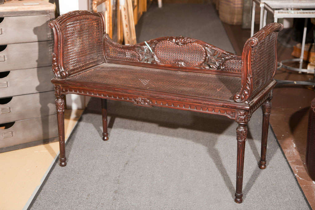 French Louis XVI style banquette, circa 1940s, serpentine back with raised arms, caned seat and sides, raised on tapering fluted legs. Stamped Jansen.
