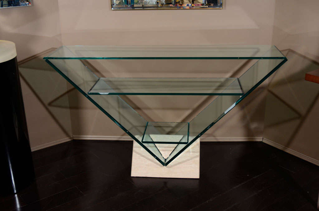 Italian glass triangular console with three glass shelves and travertine base.