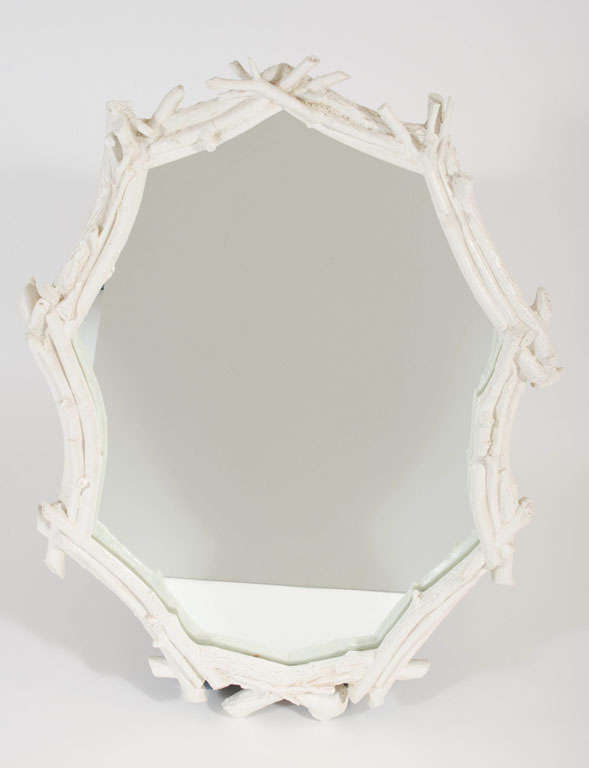 A faux bois mirror in an oval form comprised of interlocking tree 