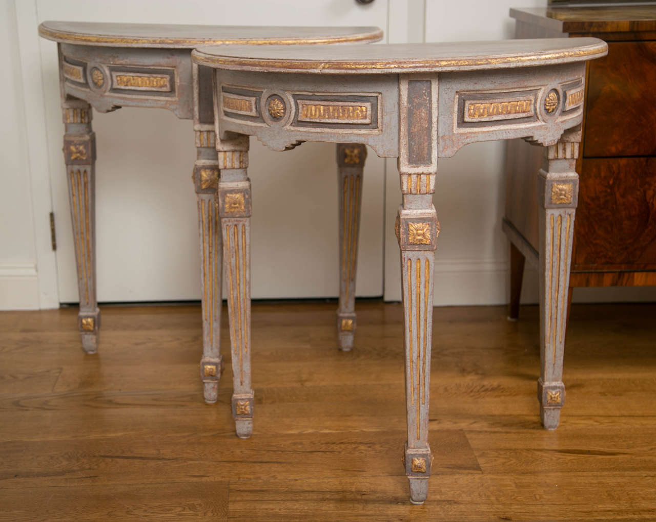 A wonderful pair of Baltic greige painted d-shaped consoles, each on three ample squared and tapered legs embellished with gilded carvings typical of the Louis XVI period, Germany, last quarter of 18th century. Paint has been refurbished.