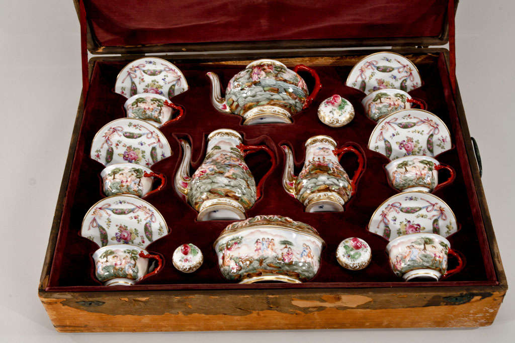 This incredible early 19th century porcelain tea and coffee service with six matching cups and saucers is still in the original fitted wooden box. Each piece is individually hand-painted over raised and molded decoration. The handles all depict a