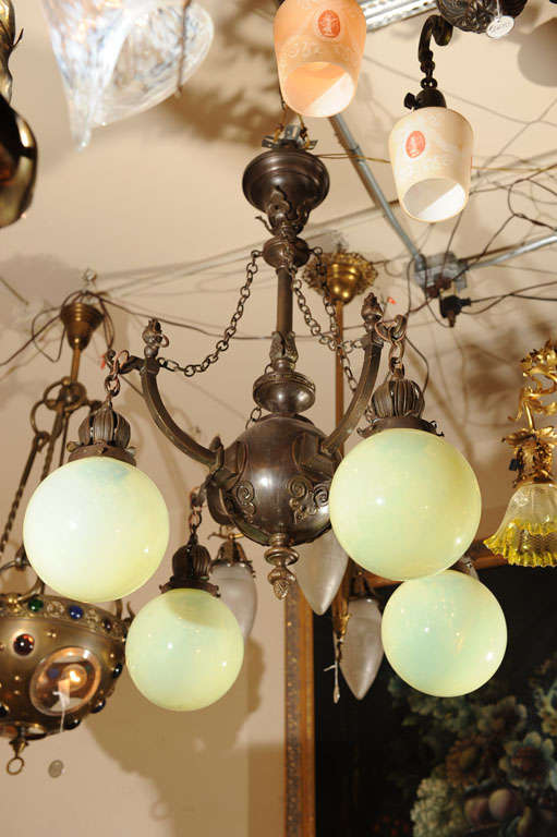 Very elegant chandelier from the turn of the century with attractive metal work and four original oversized, hard-to-find blown vaseline glass shades.  The fixture also has four gas jets which are no longer active and now act as an ornamental