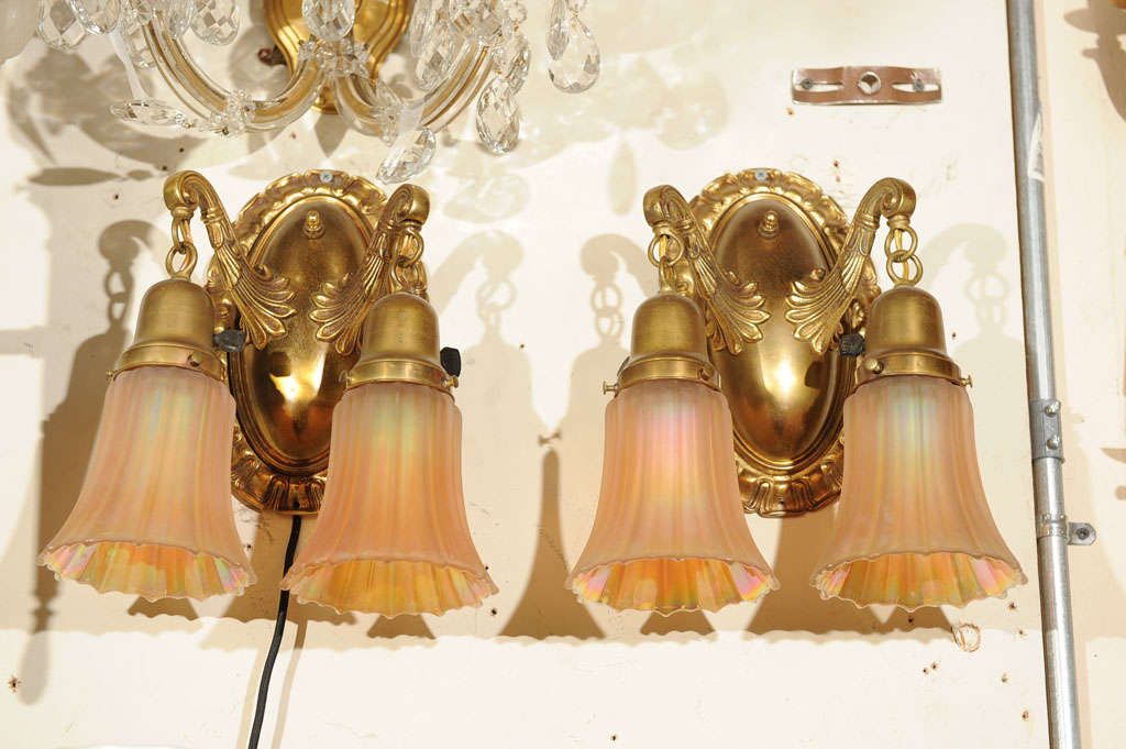 These well cast bronze sconces are in a beautiful rich gold brown patina and have a strong and substantial presence.  The arms and the backplates are cast bronze, not spun metal.  They come with period carnival glass shades that exhibit great