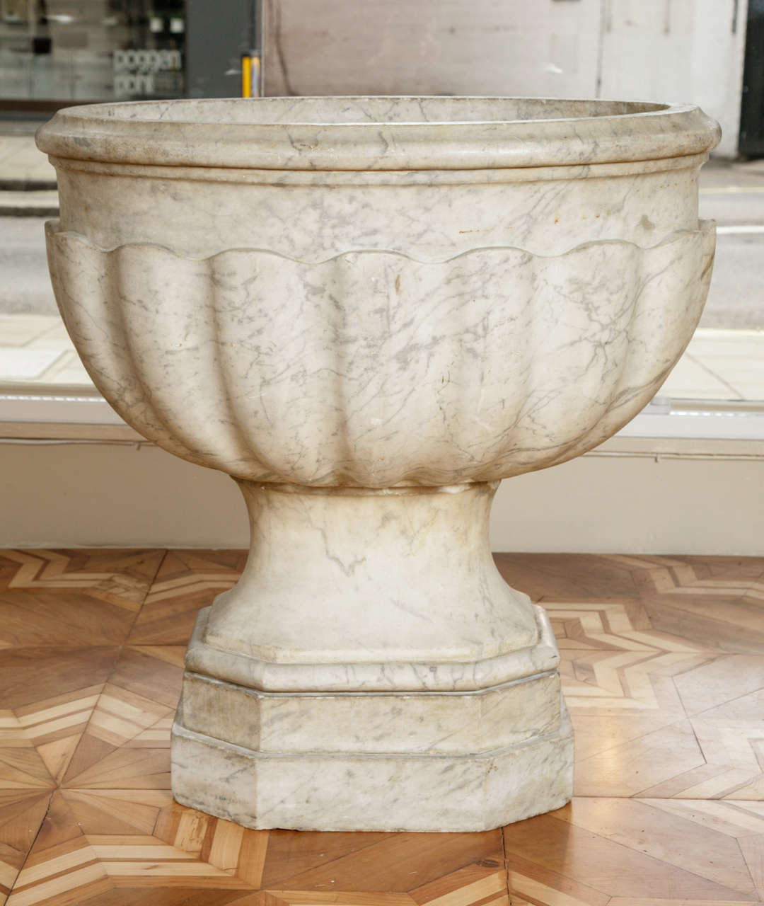 A substantial cistern, carved out of grey and white marble. With a moulded lip above a gadrooned basin, on a waisted support with lozenge-shaped base. 

Measurements: 27 1/2