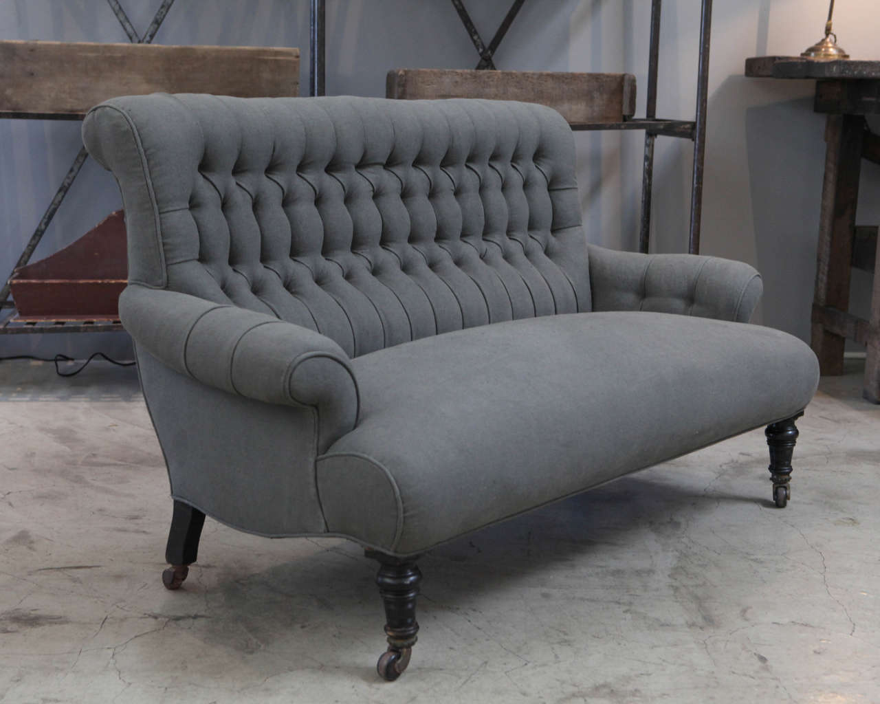 a handsome settee newly upholstered in dark gray linen with it's original frame and wooden wheel feet.
