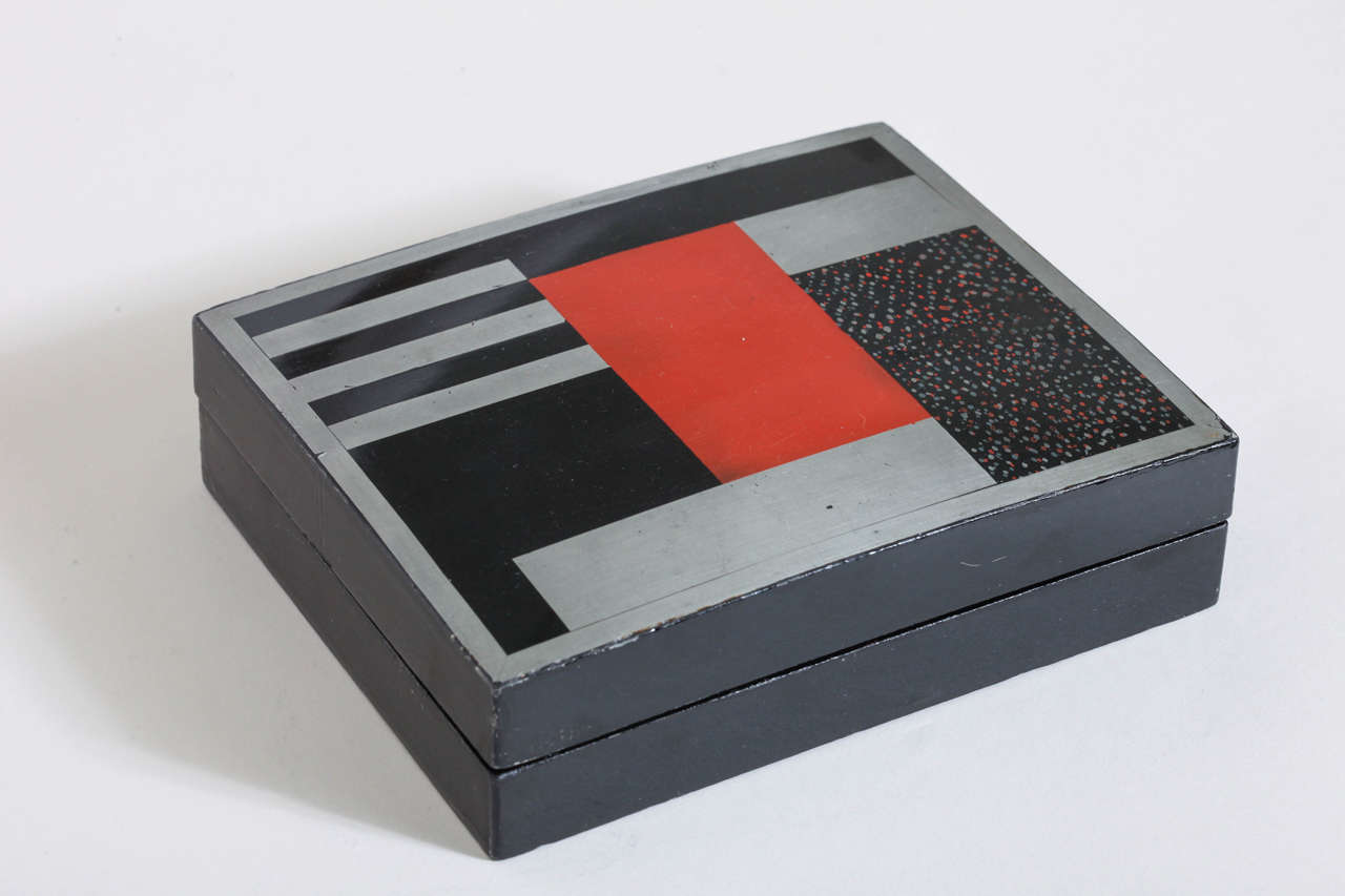 Black lacquered box with silver and red modernist design.