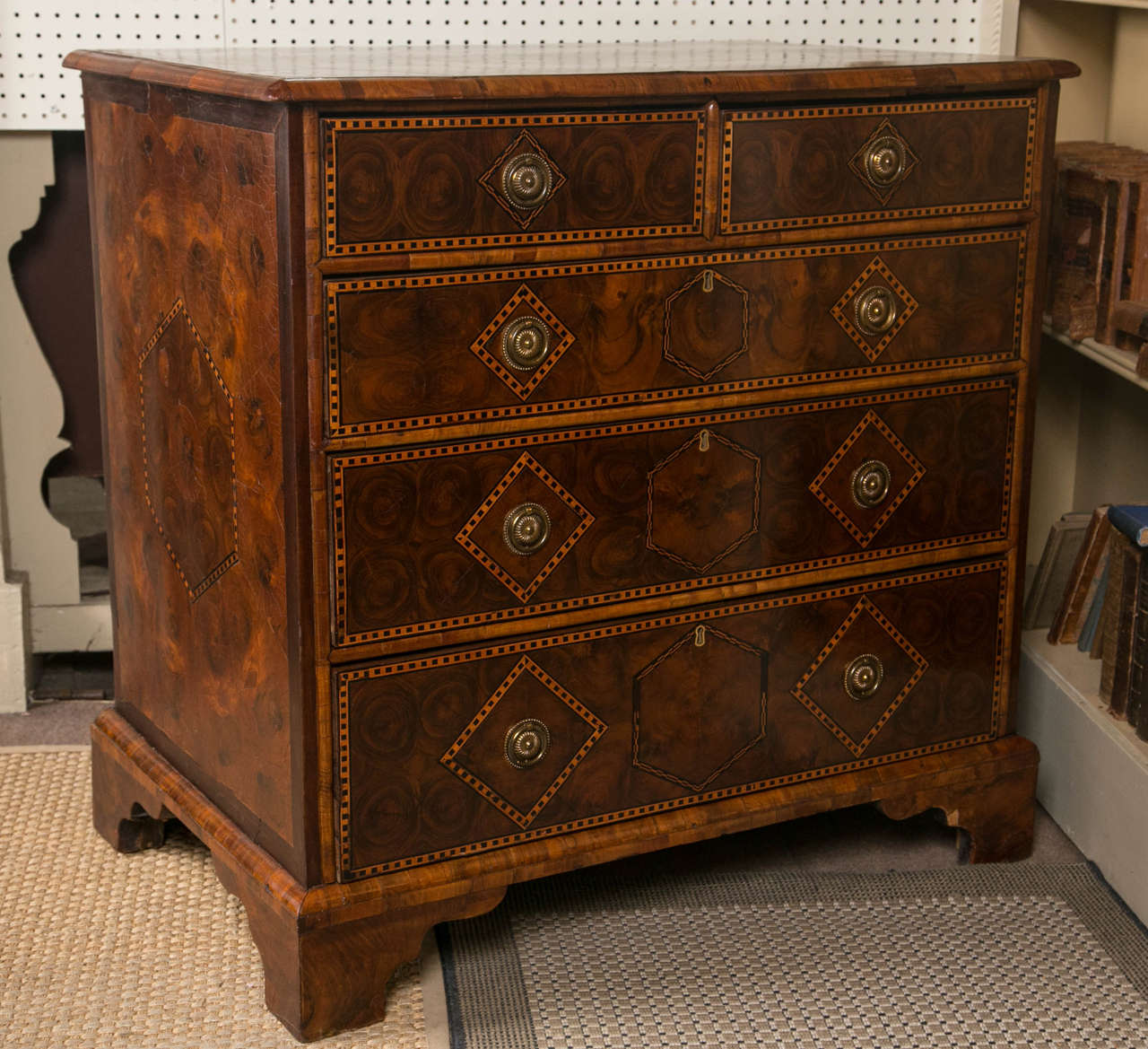 This oyster walnut chest has  five drawers. The three below are  graduated in depth. Ebony and satinwood inlays in checker pattern decorate  the top, band the drawers fronts and surround the pulls and key holes (no key). The sides are inlaid  with