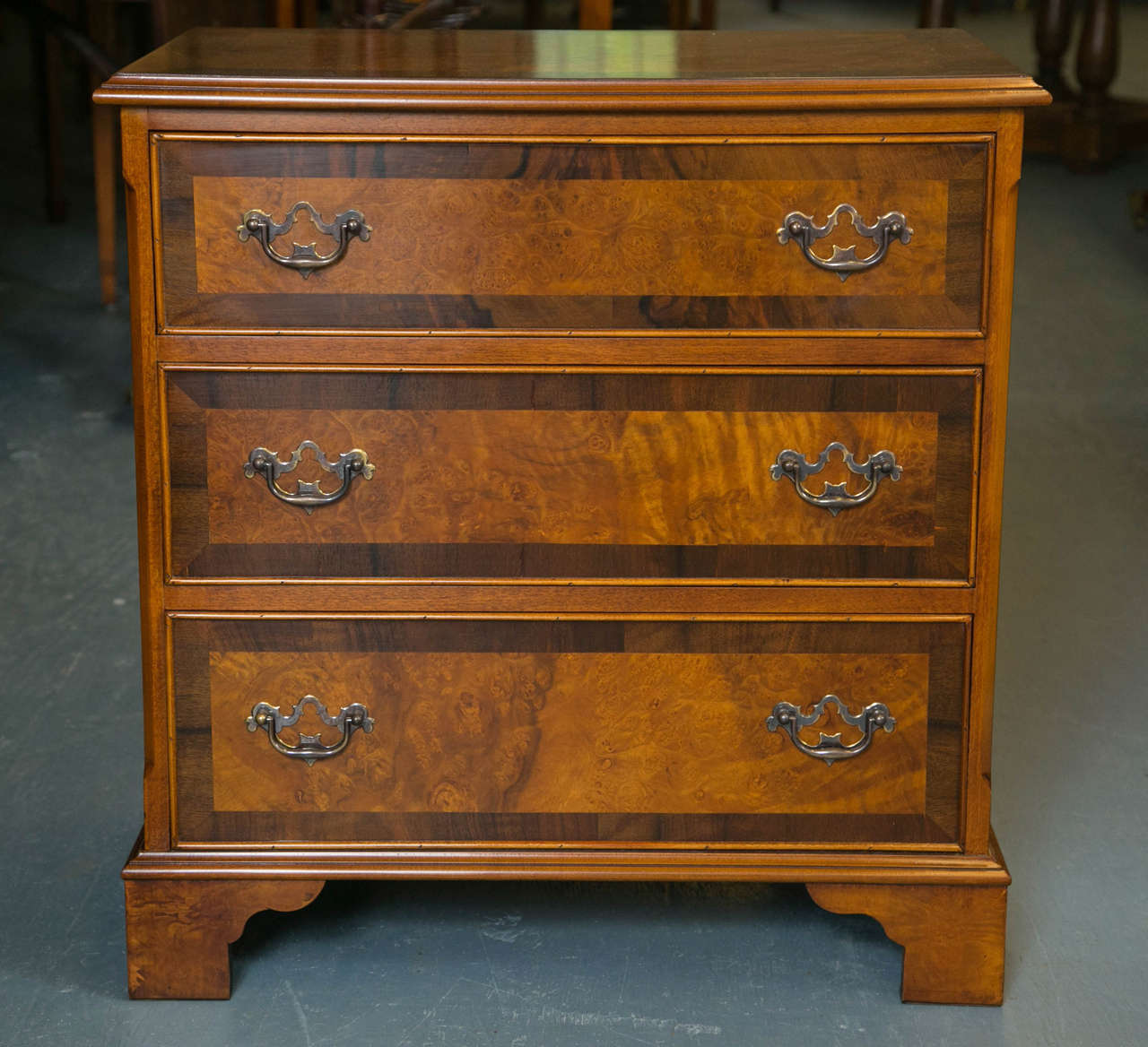 Custom made for us by English cabinet makers, this Classic little three-drawer chest in walnut burl has chamfered corners and rests on bracket feet. The top and drawer fronts are crossbanded in a contrasting straight grain walnut that reins in the