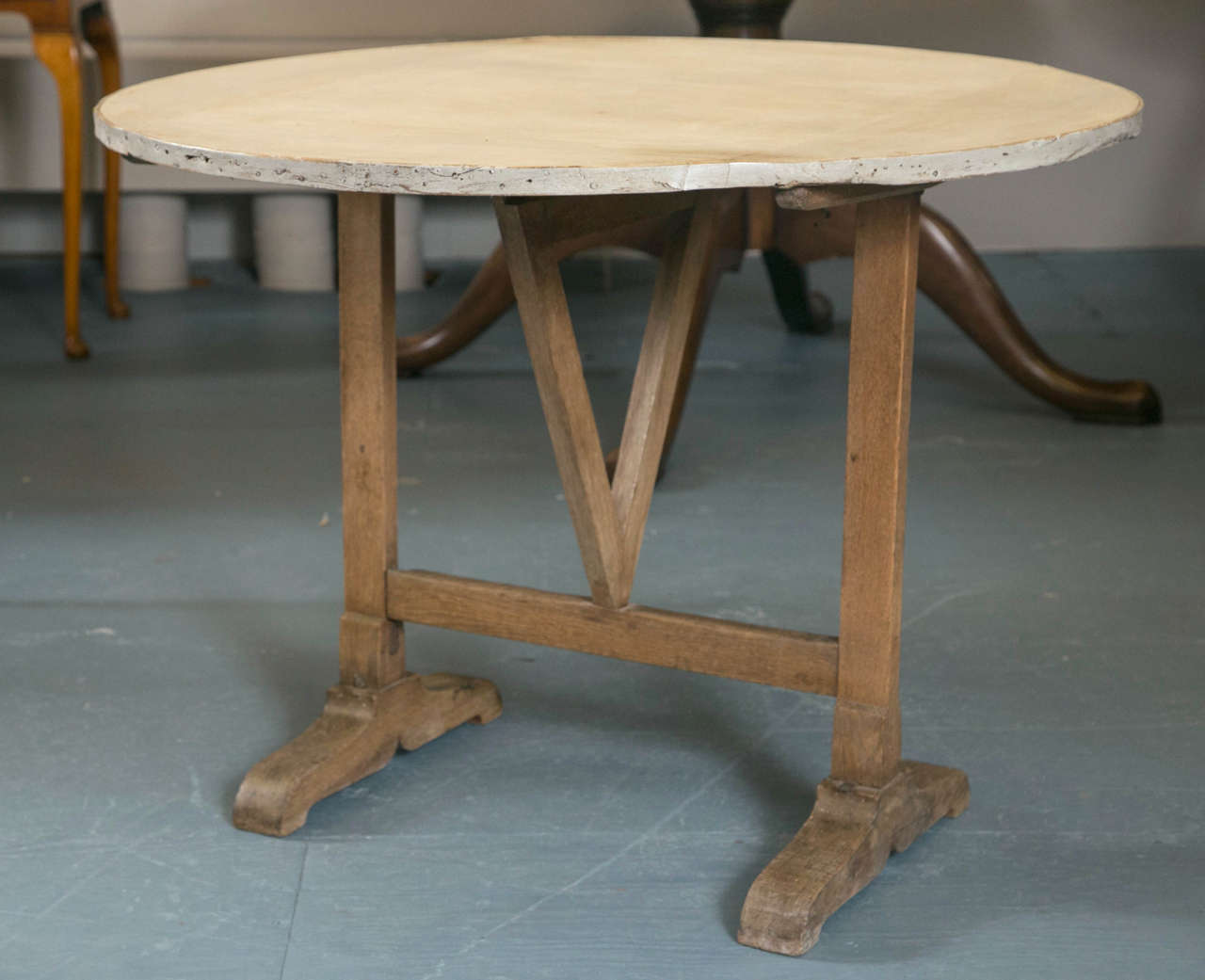 A pale grey painted top on a rustic fruitwood base of typical form give this tilt top table a genuine country look. The paint has some age, but is in good condition. However, it would not be a travesty to repaint the top, since this particular table