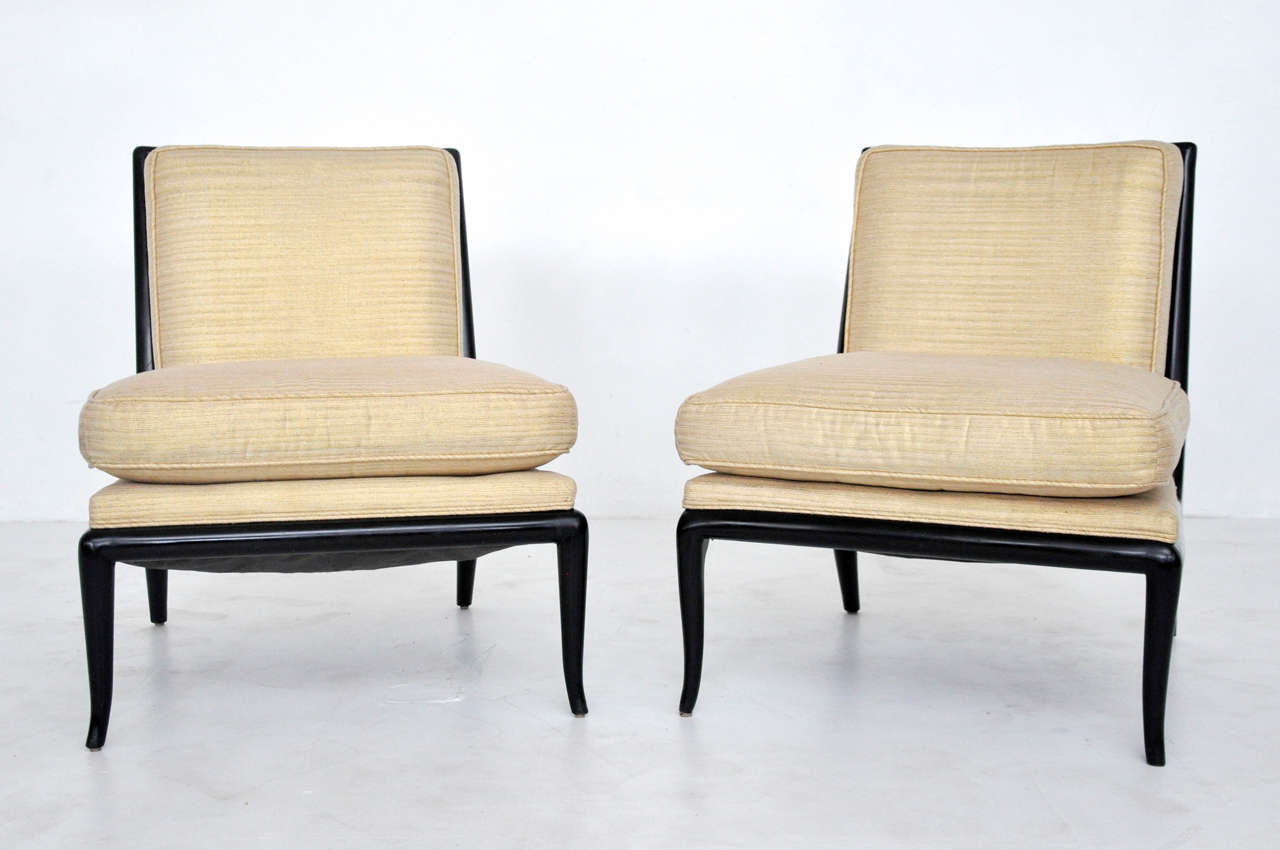 Pair of slipper chairs designed by T.H. Robsjohn-Gibbings. Excellent vintage condition. Polished black lacquer frames with metallic gold tone fabric.
