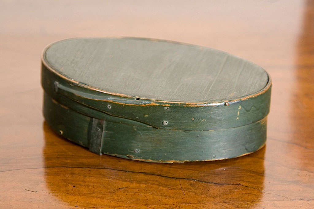 19th c. oval bentwood pantry box with single fingered lid in original green paint. Constructed from pine with overlapping seams, tacked joints and metal clinch. Box is accompanied by a sales receipt dated November 1966 tucked inside.