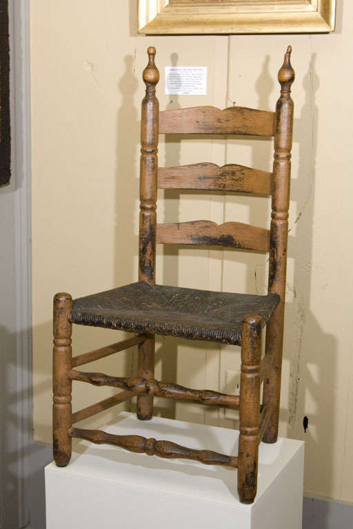 A Bergen County New Jersey childs chair with attenuated urn finials and three shaped slats above a rushed seat, sausage turned legs, and two vase and ring turned front stretchers. Seat height is 11 3/4
